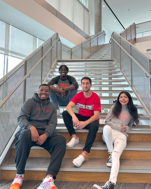 Four people sitting on staircase inside University Commons