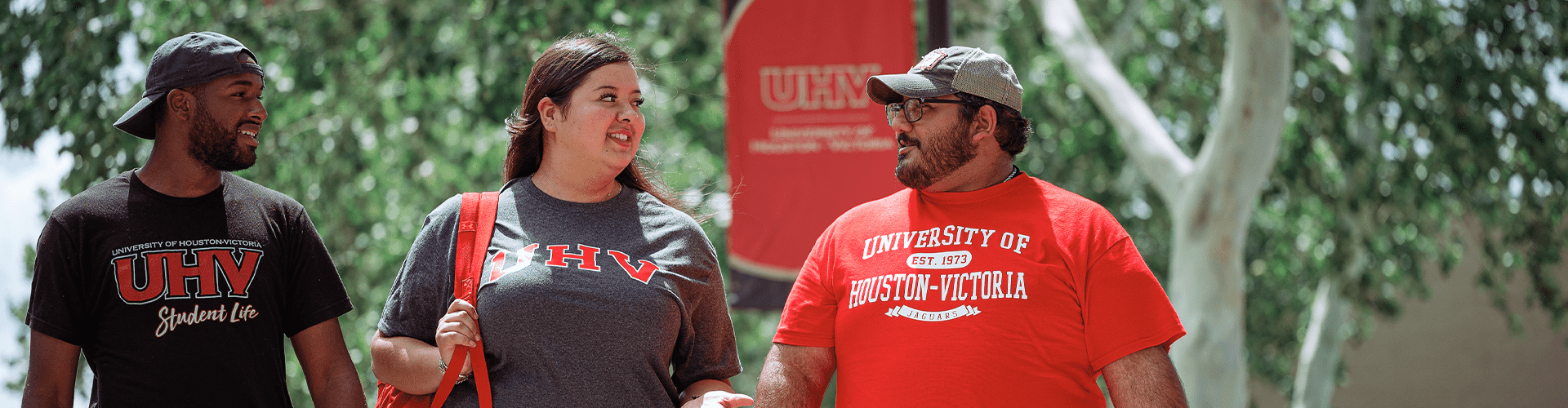 Three students walking outside, wearing UHV apparel.