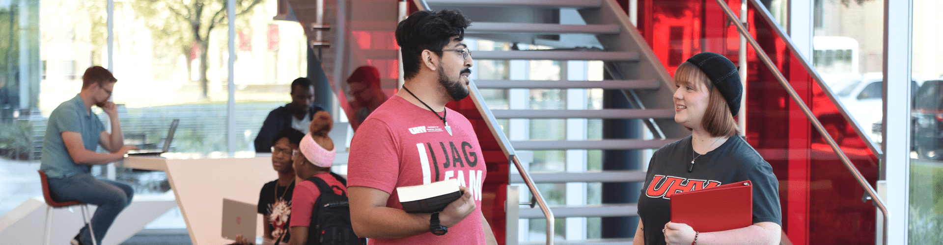 UHV students talking and studying in University South with large windows and a staircase