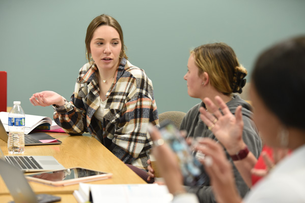 Three students in a classroom talking