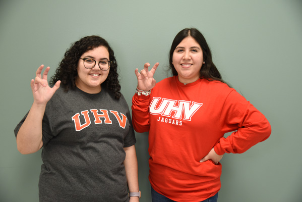 Two students holding up the UHV hand sign.