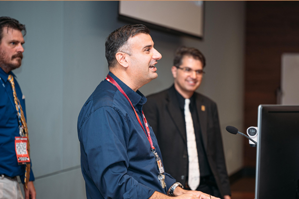 Dr. Nusayr stands behind a podium, with two other professors beside him.