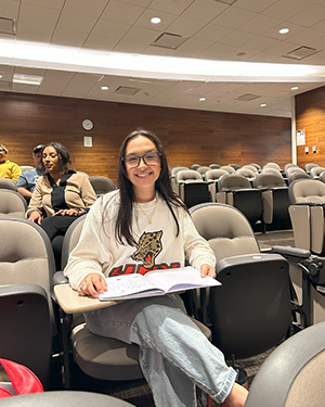 Student in lecture hall reading an open book at desk