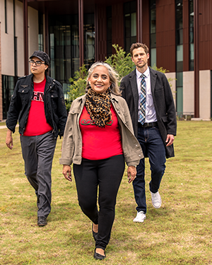 Three UHV professors walking confidently across campus lawn.