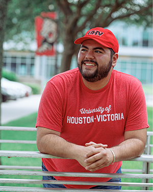 Person in red UHV shirt and cap leaning on railing