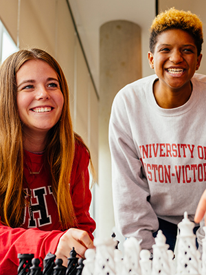 Two people playing chess, wearing UHV sweatshirts