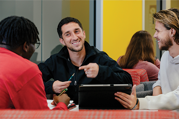 Three male students laughing while studying.