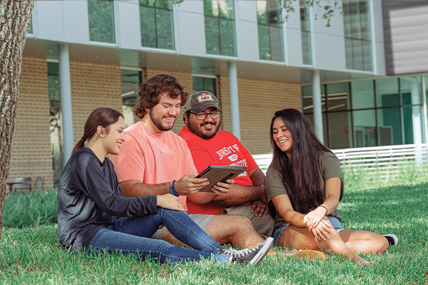 Four students sitting on grass