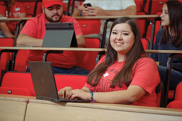 A female student, with a laptop, sitting in an auditorium. A female student, with a laptop, sitting in an auditorium.