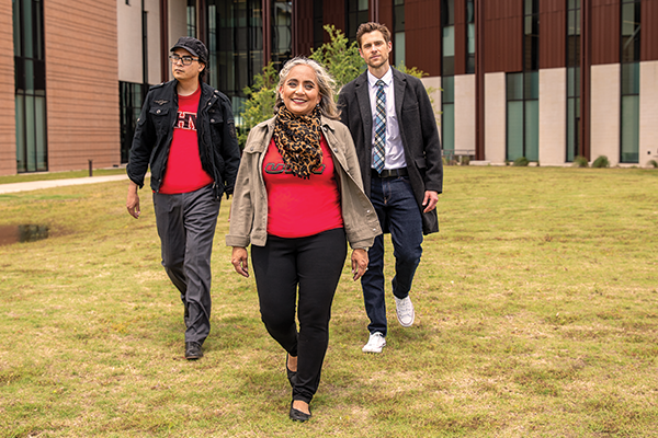 An instructor with students, walking across campus.