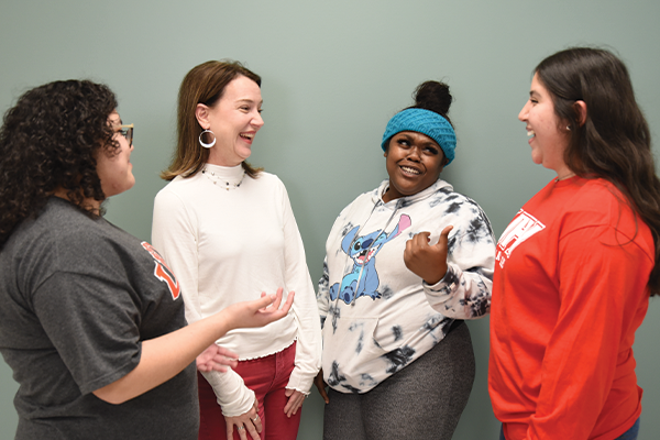 An instructor and students, laughing and engaged in discussion.