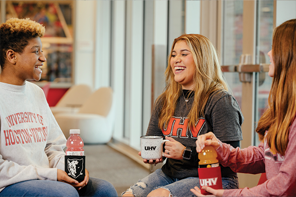 Three female students showing off UHV apparel and merchandise.
