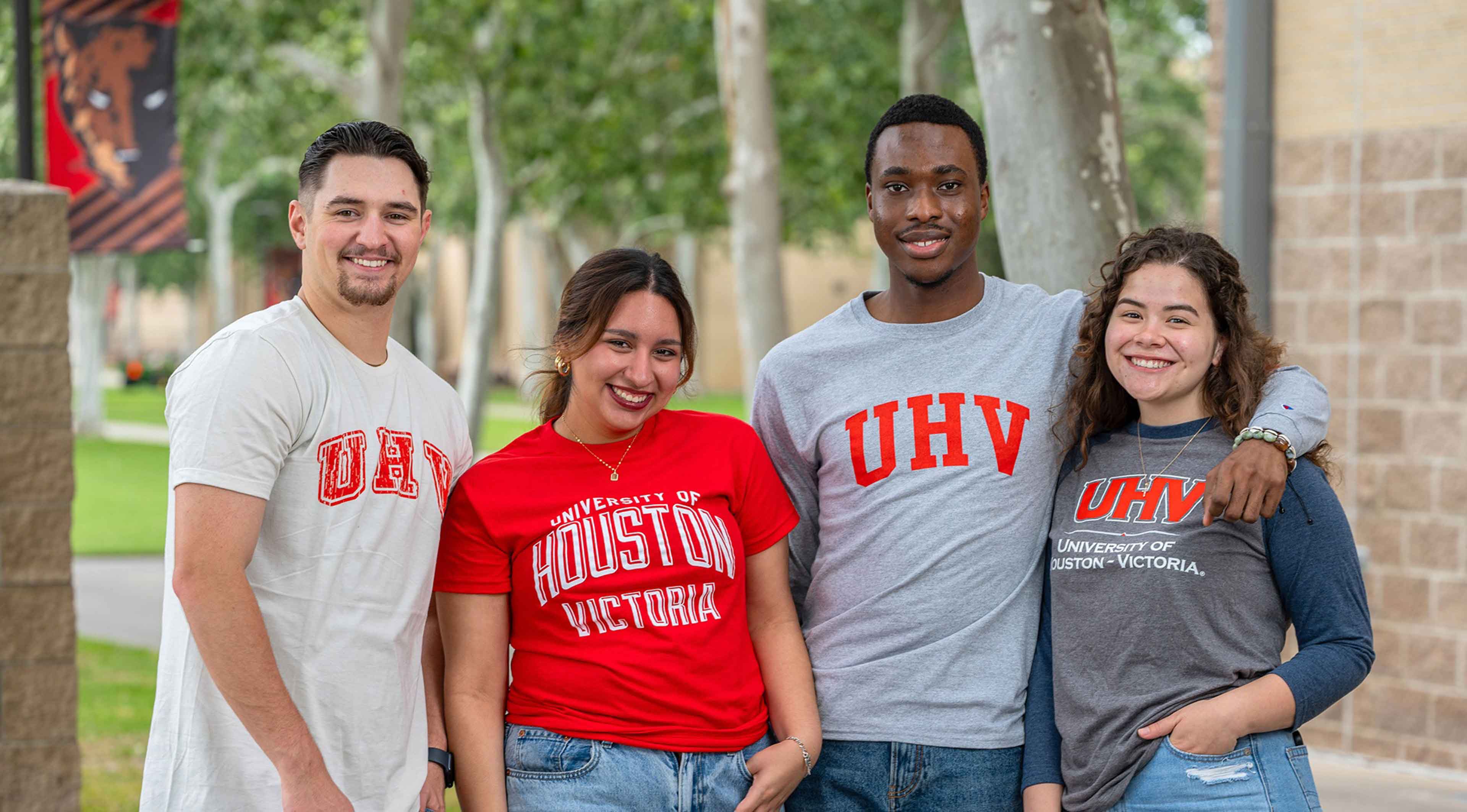 Four UHV students standing together outside on campus