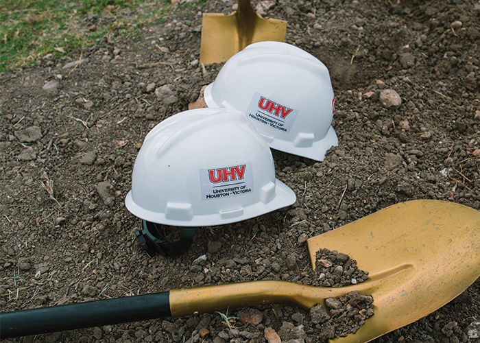 White hard hats with UHV logos on them and a gold shovels used at groundbreaking event