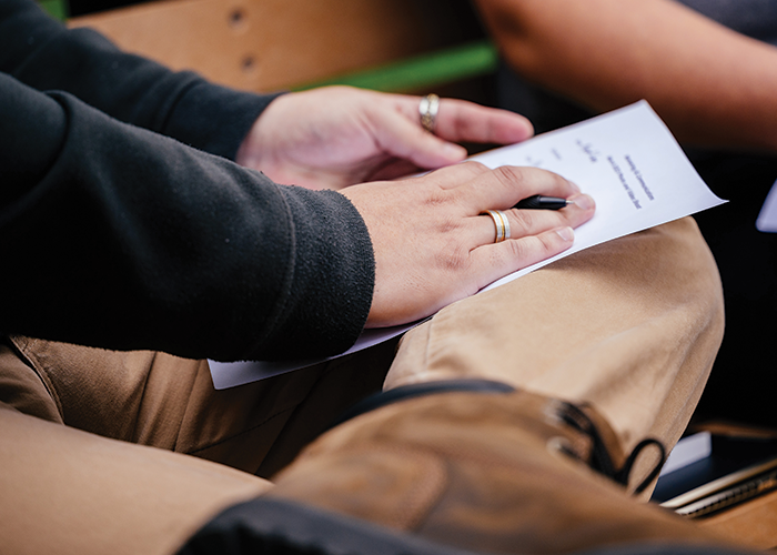 A person seated and holding a piece of paper with both hands.