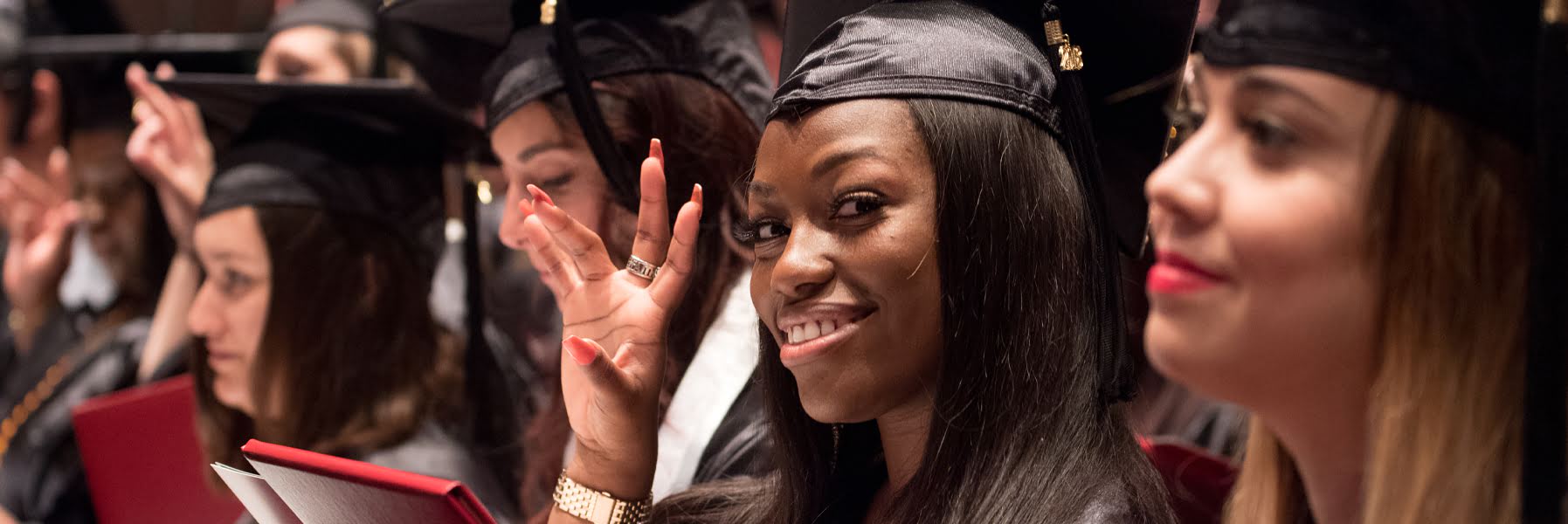 Female student doing UHV Hand Sign at graduation