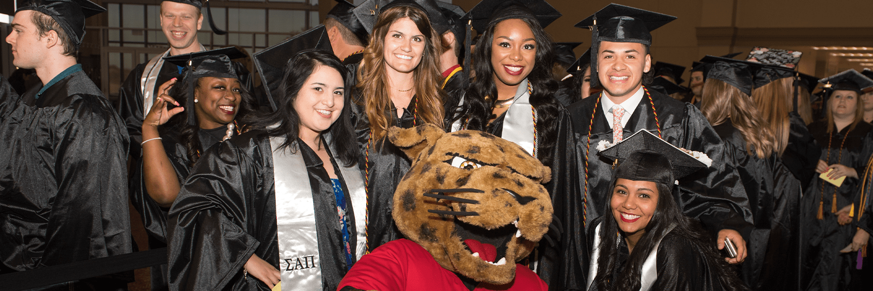 students posing with jaX at graduation.