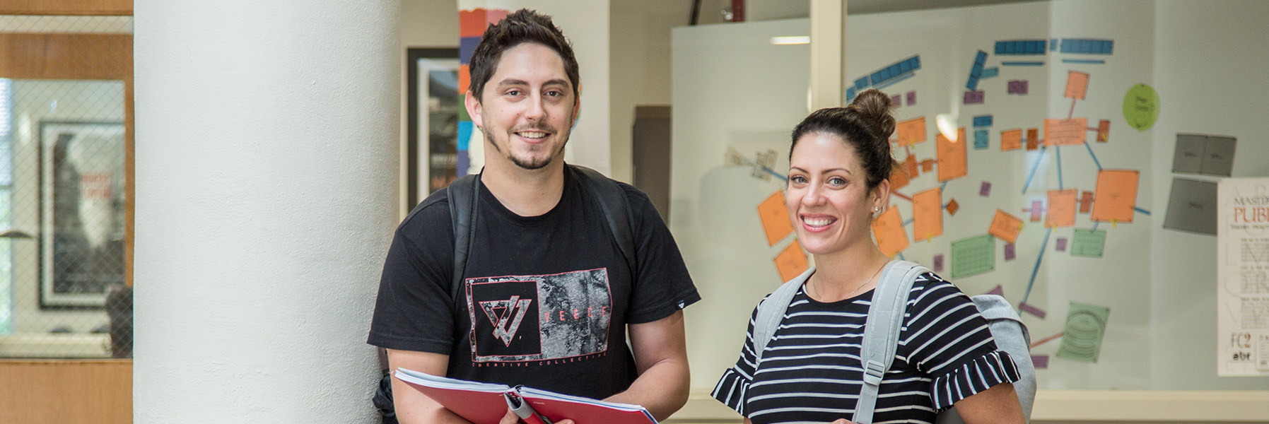Two students posing while holding abook.