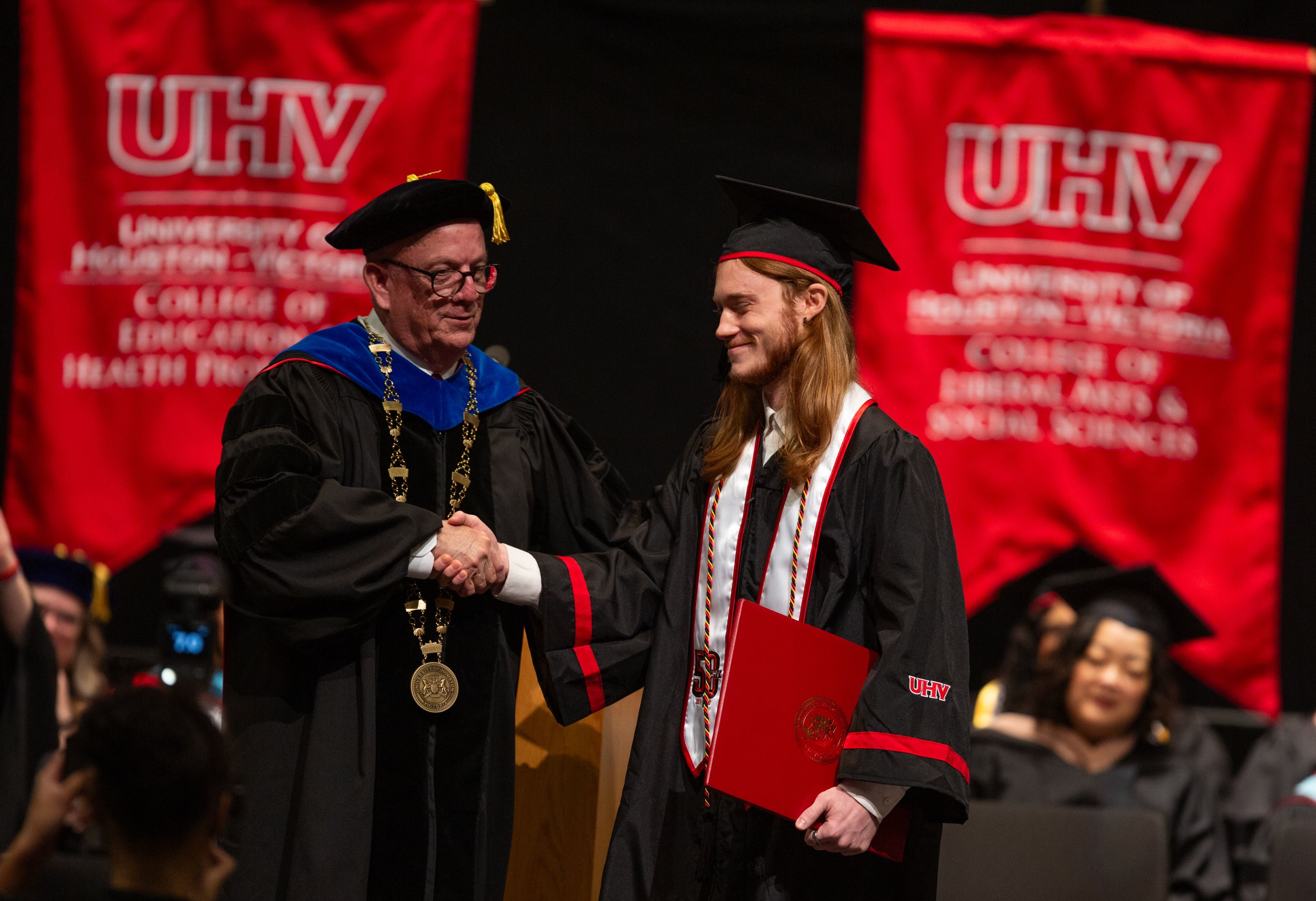 UHV President Bob Glenn shakes a graduating student's hand.