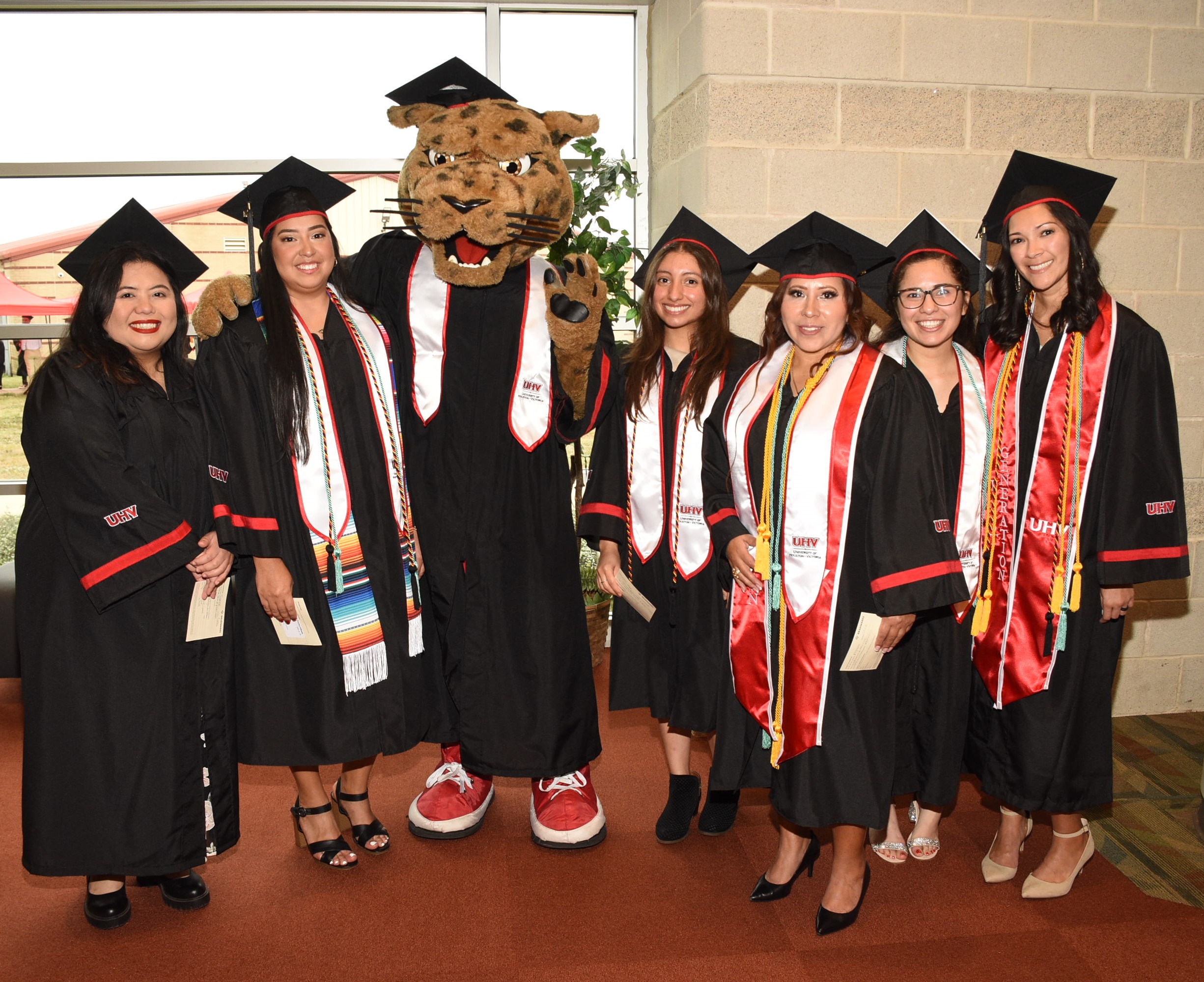 A group of graduates pose with UHV mascot jaX.