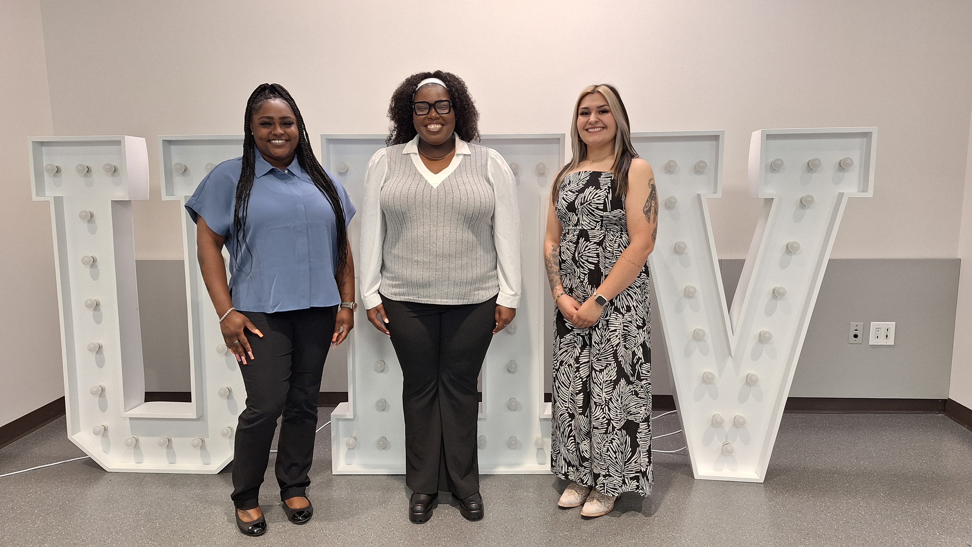 Three women stand in front of a UHV sign.