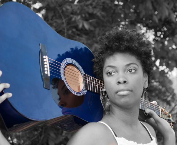 Singer-songwriter posing with a blue guitar over her shoulders