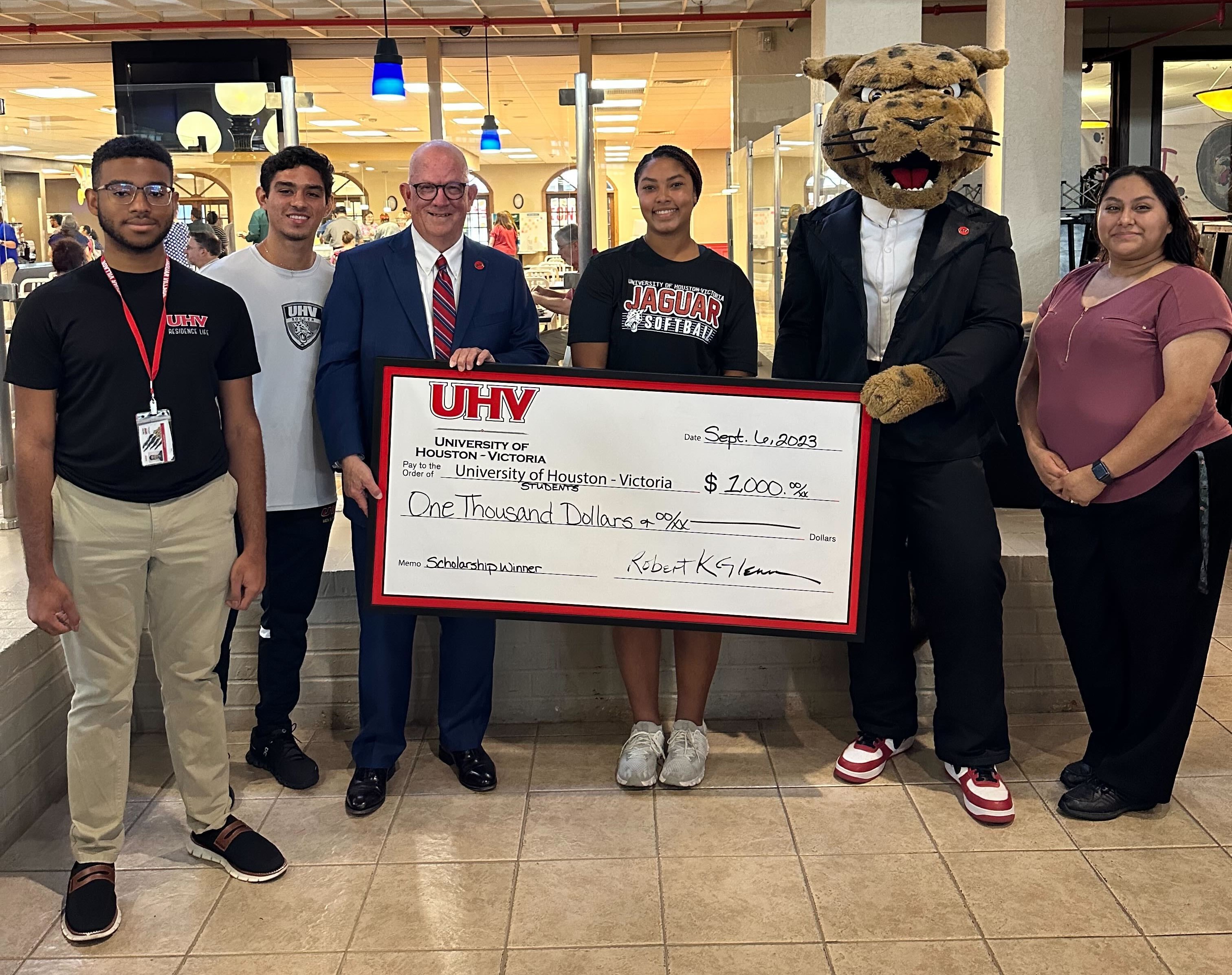 A group of University of Houston-Victoria students who won $1,000 scholarships have their picture taken Wednesday with UHV President Bob Glenn, third from left, and UHV’s mascot jaX the jaguar.