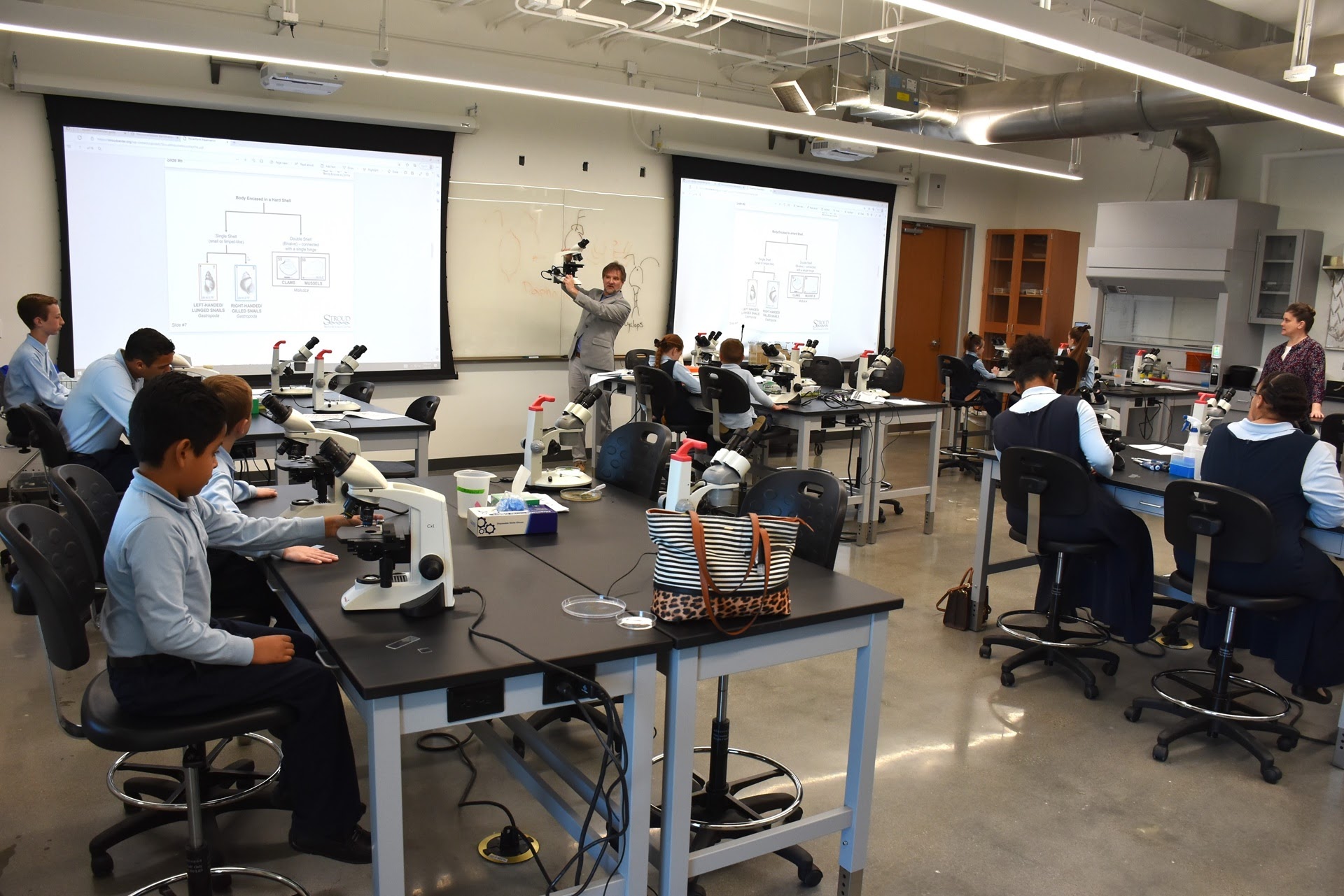 Dmitri Sobolev, in gray suit, interim dean of the UHV College of Natural & Applied Science, explains how to use a microscope Friday to students from Edna Christian Academy during an aquatic science activity at the University of Houston-Victoria.