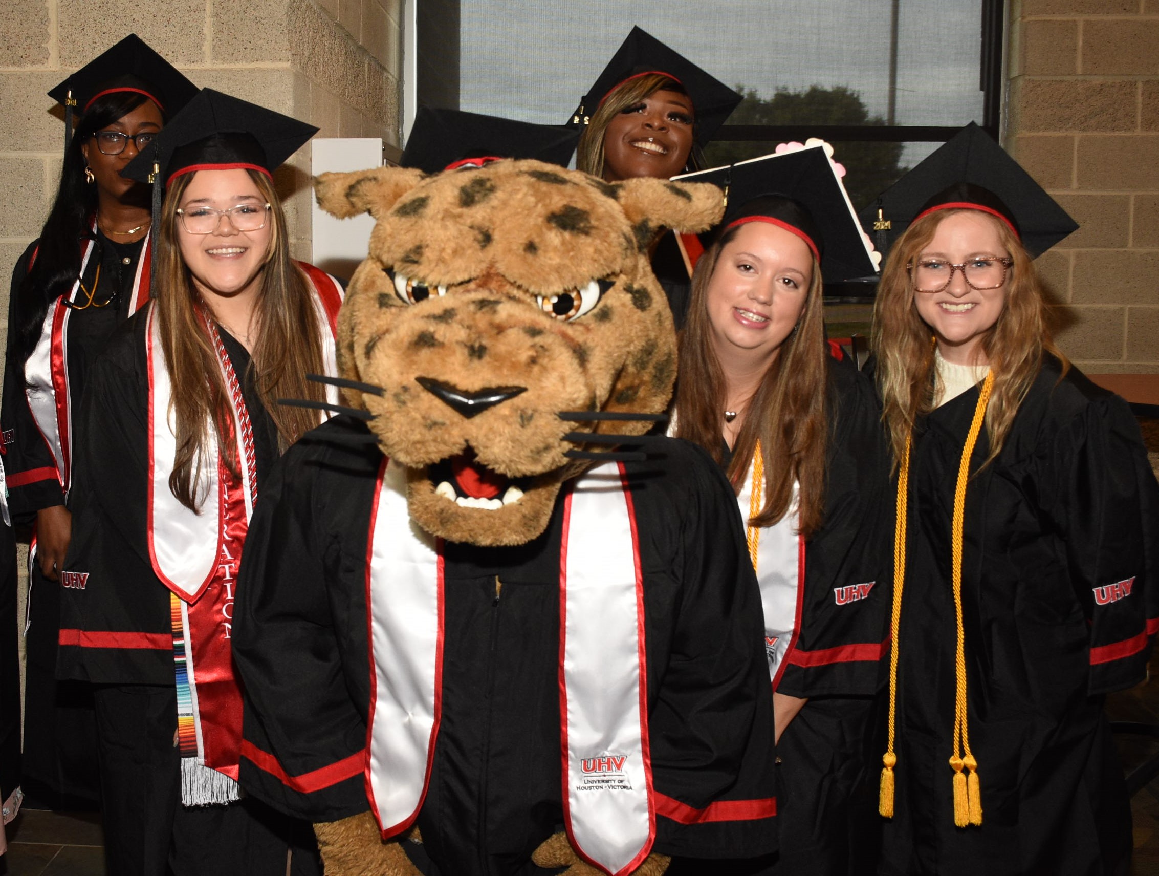 A group of graduating students pose for a photo with the UHV mascot jaX.