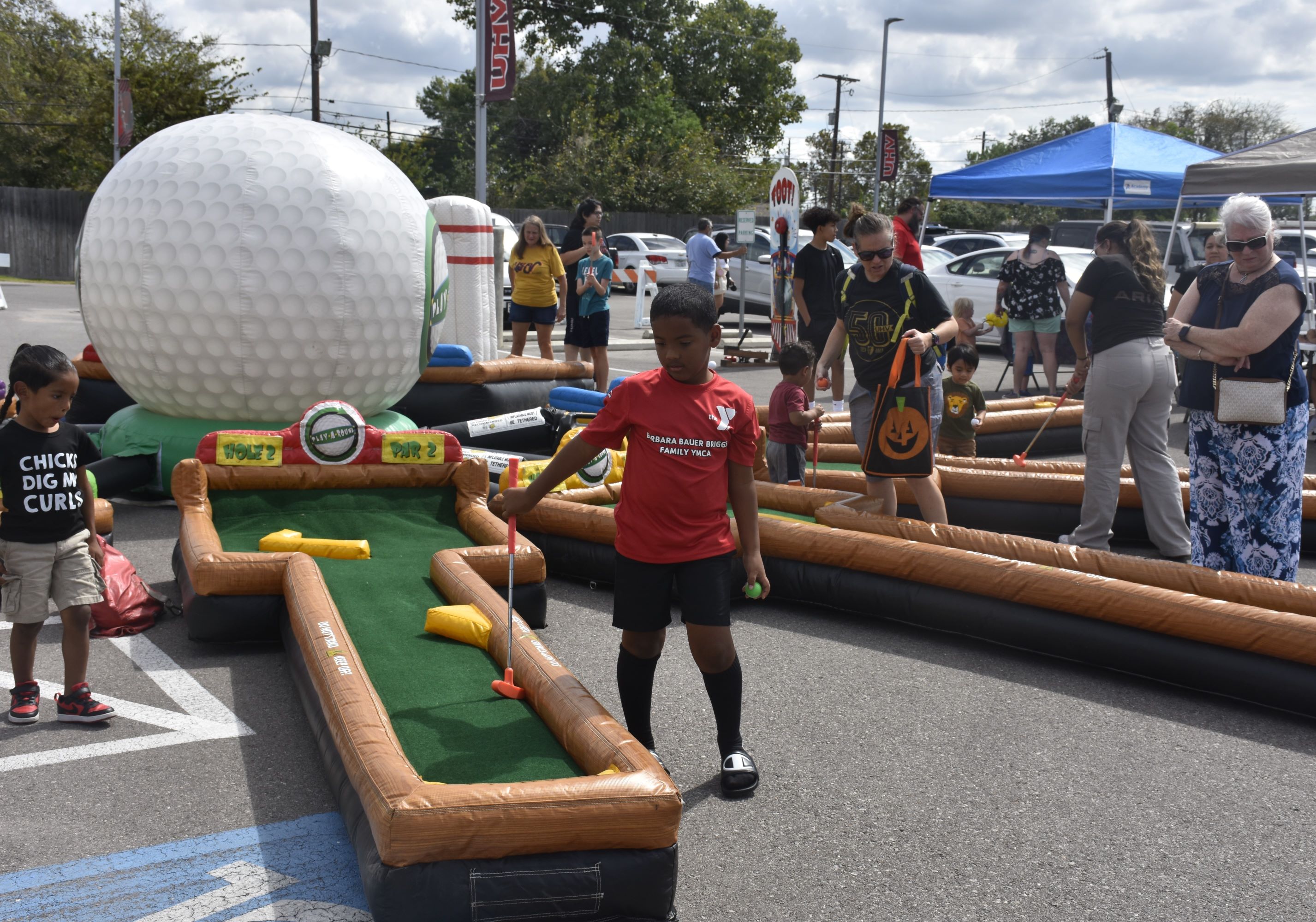 Children play putt-putt in a parking lot.