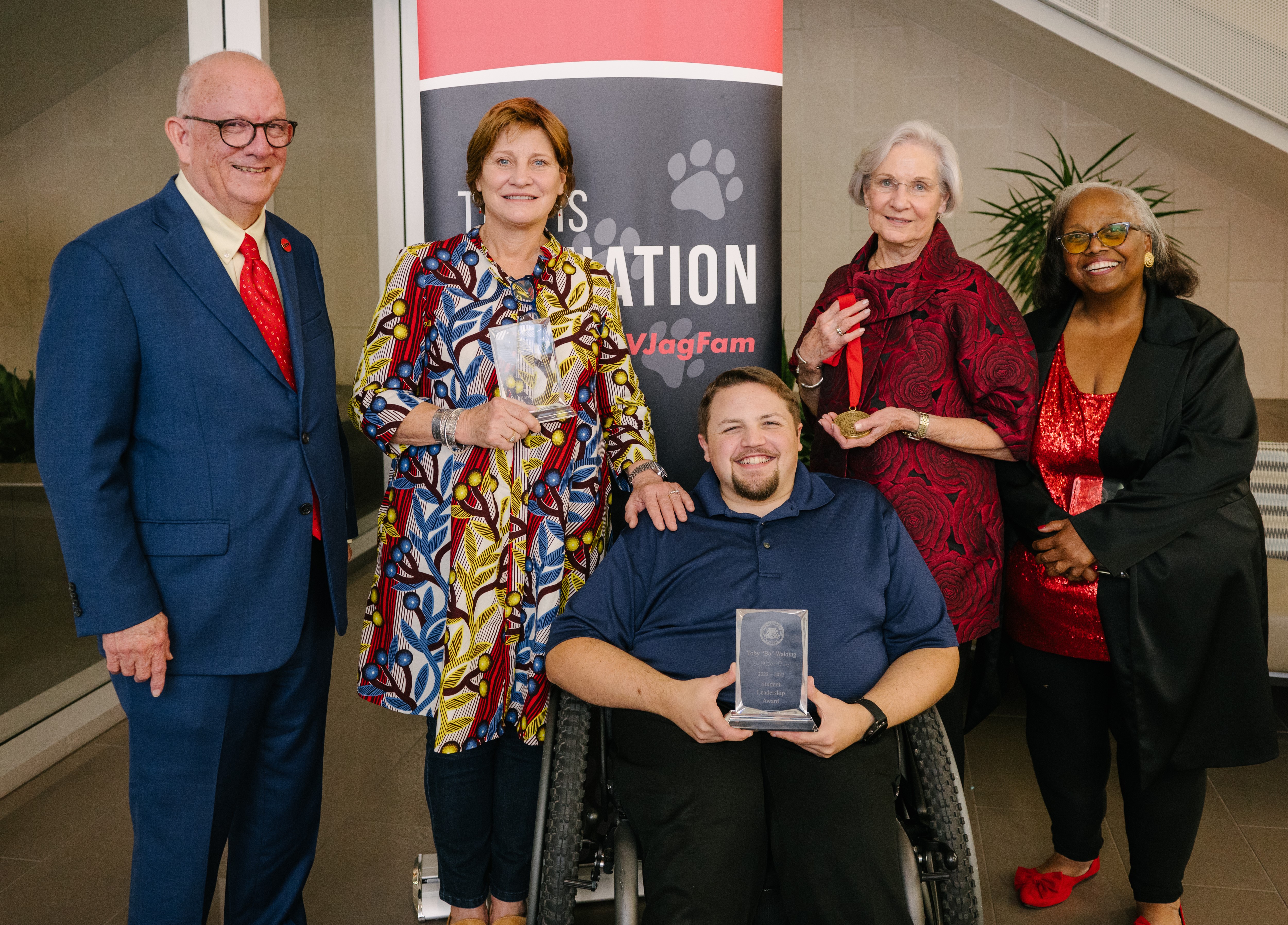 Five people pose for a photo with awards