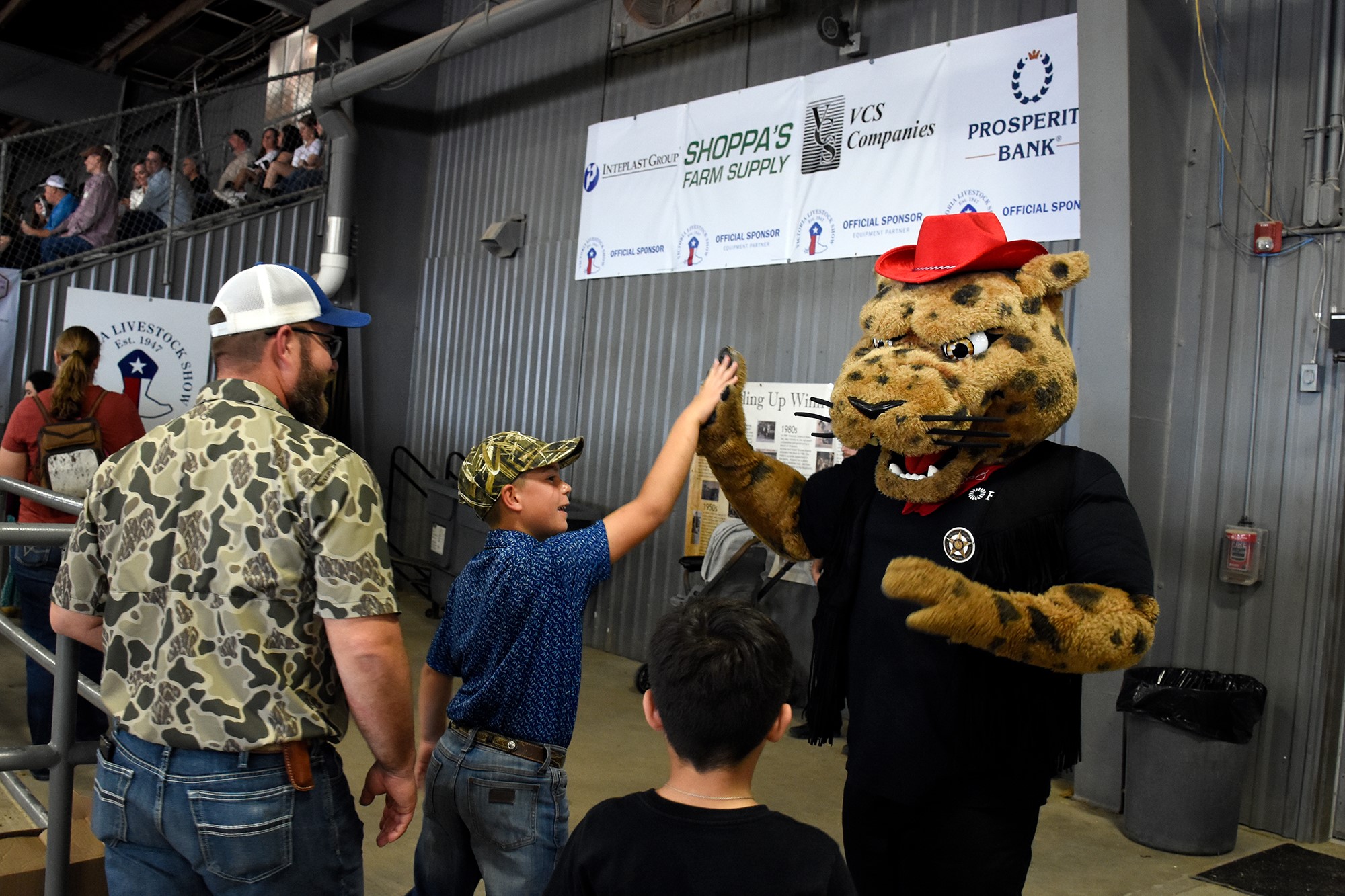 UHV's mascot jaX the Jaguar high fives a boy.
