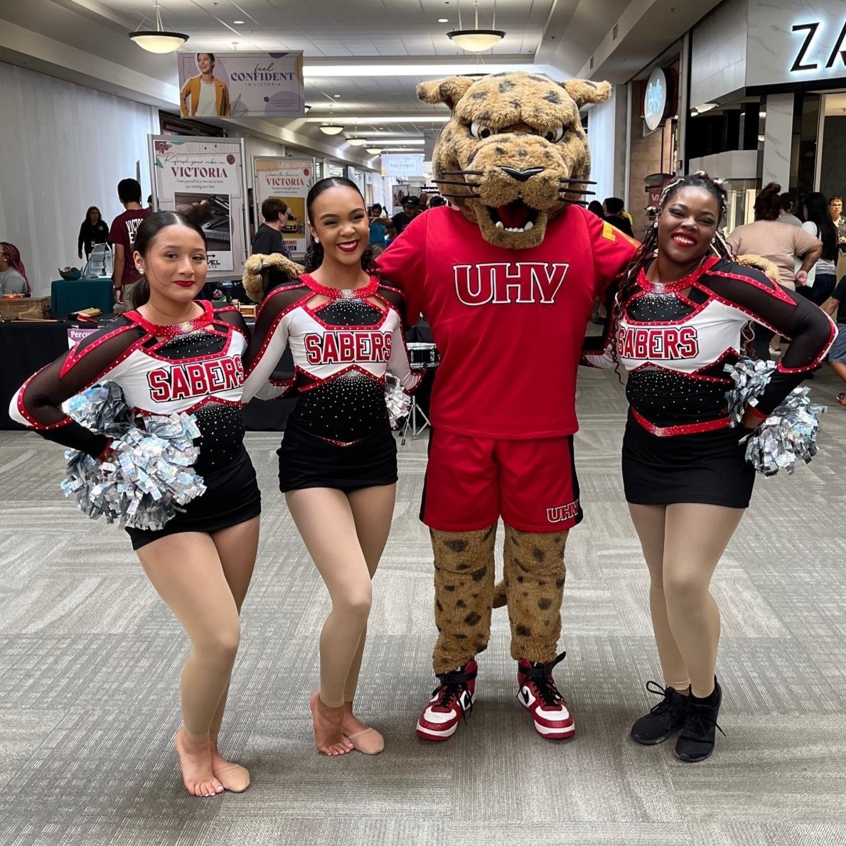 UHV's mascot jaX the Jaguar stands with three high school cheerleaders.