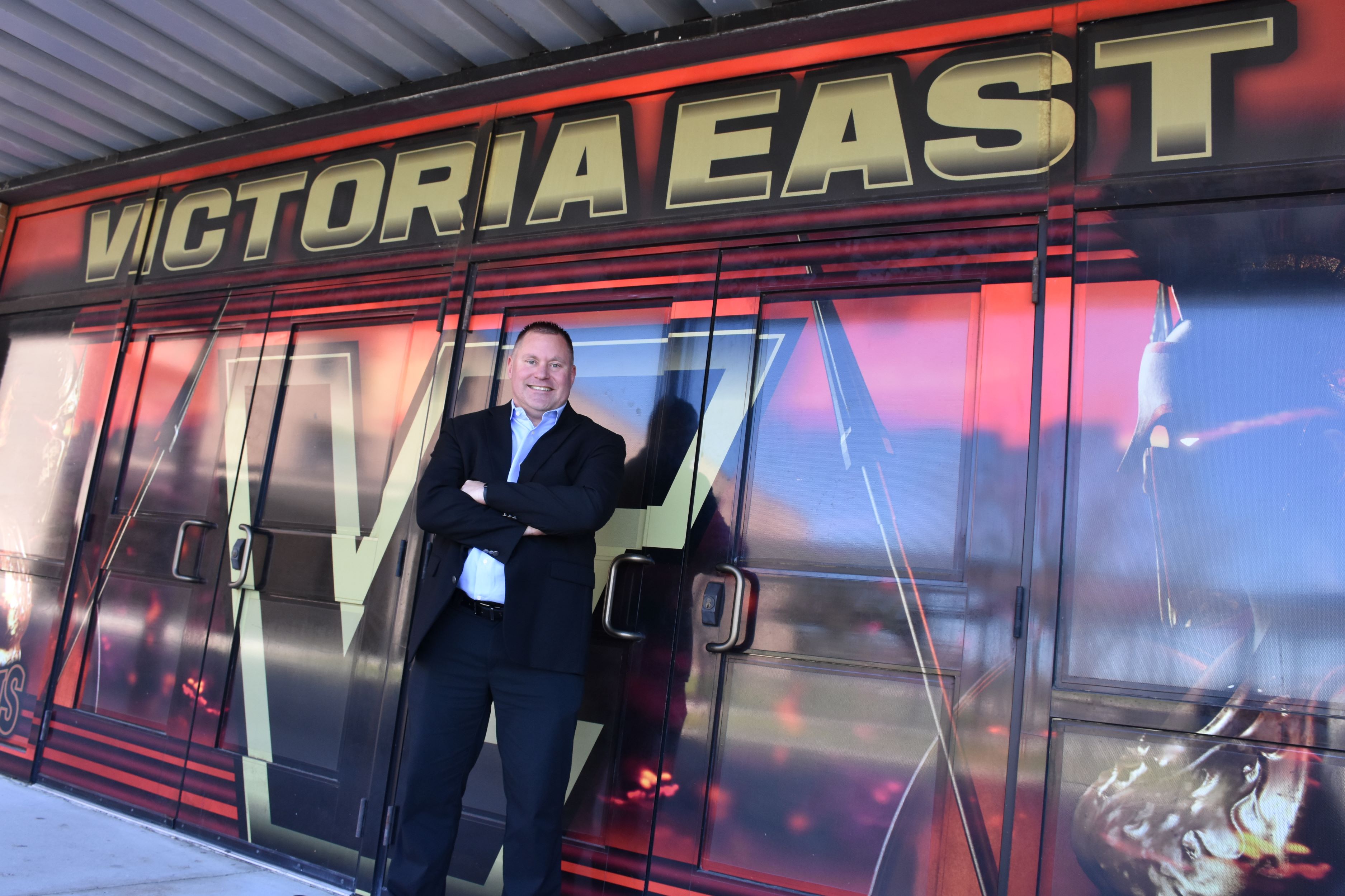 Justin Gabrysch stands in front of a Victoria East mural