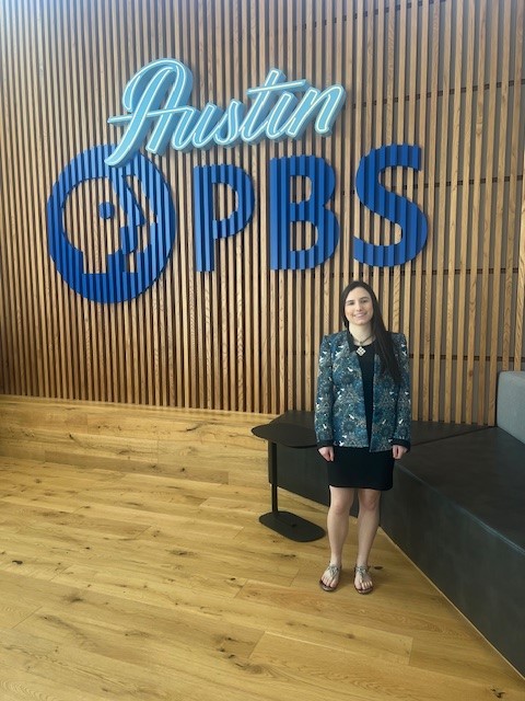 Katie Amatangelo stands with an Austin PBS sign.
