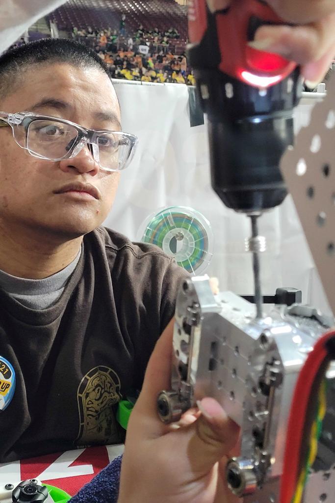 UHV student Kristian Pulido supervises as a person works on a robot.