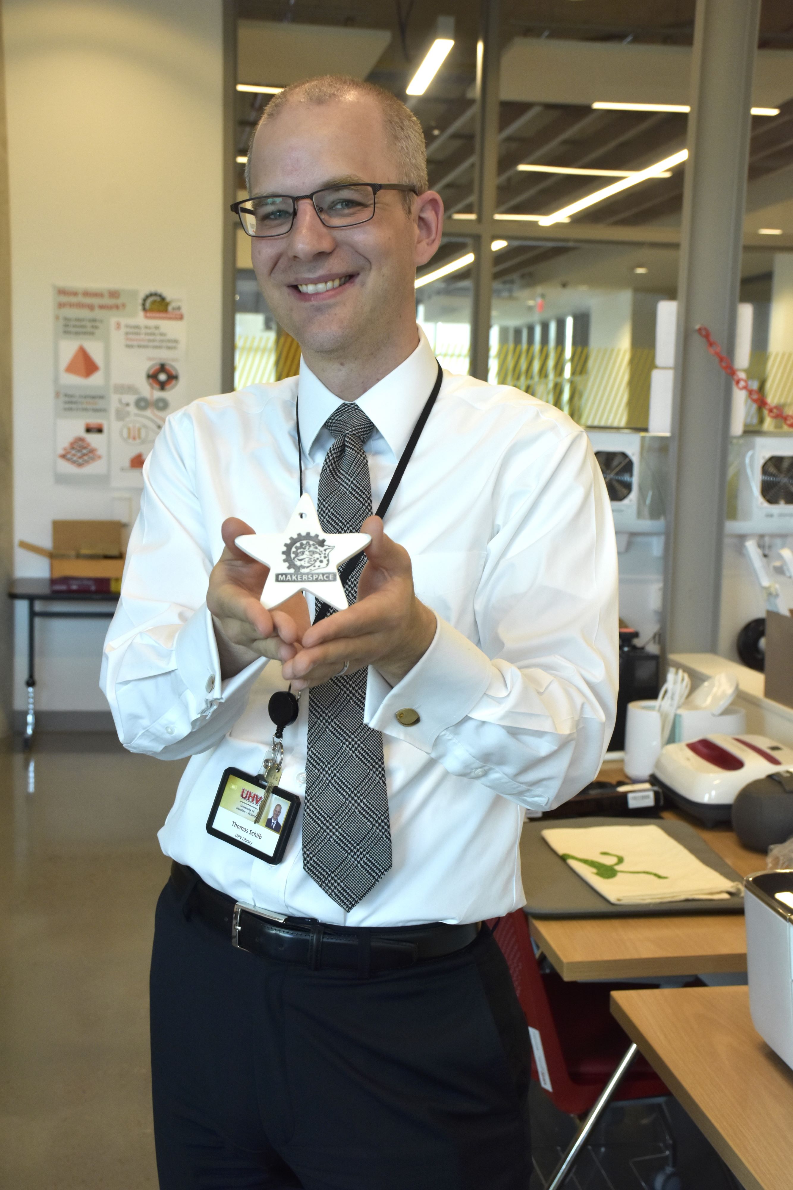Tom Schilb holds a star-shaped ornament that has the word Makerspace burned into it.