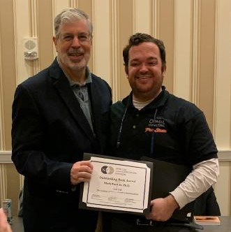 Mark Ward, left, receives the Outstanding Edited Volume of 2023 by the Spiritual Communication Division of the National Communication Association for his book “God Talk: The Problem of Divine-Human Communication” on Nov. 17 during the NCA's convention.