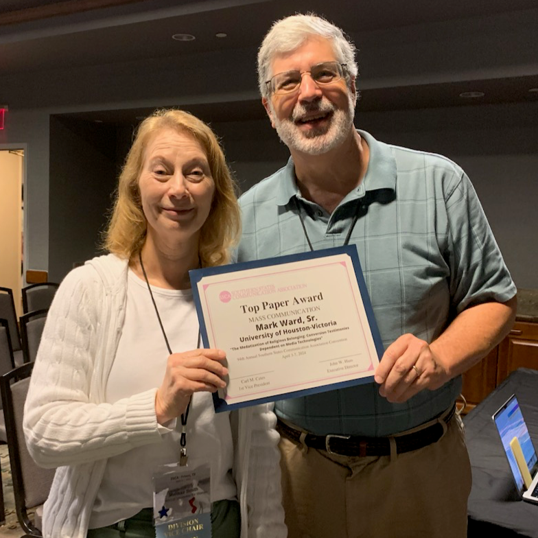 Mark Ward receives a paper certificate award from a woman.