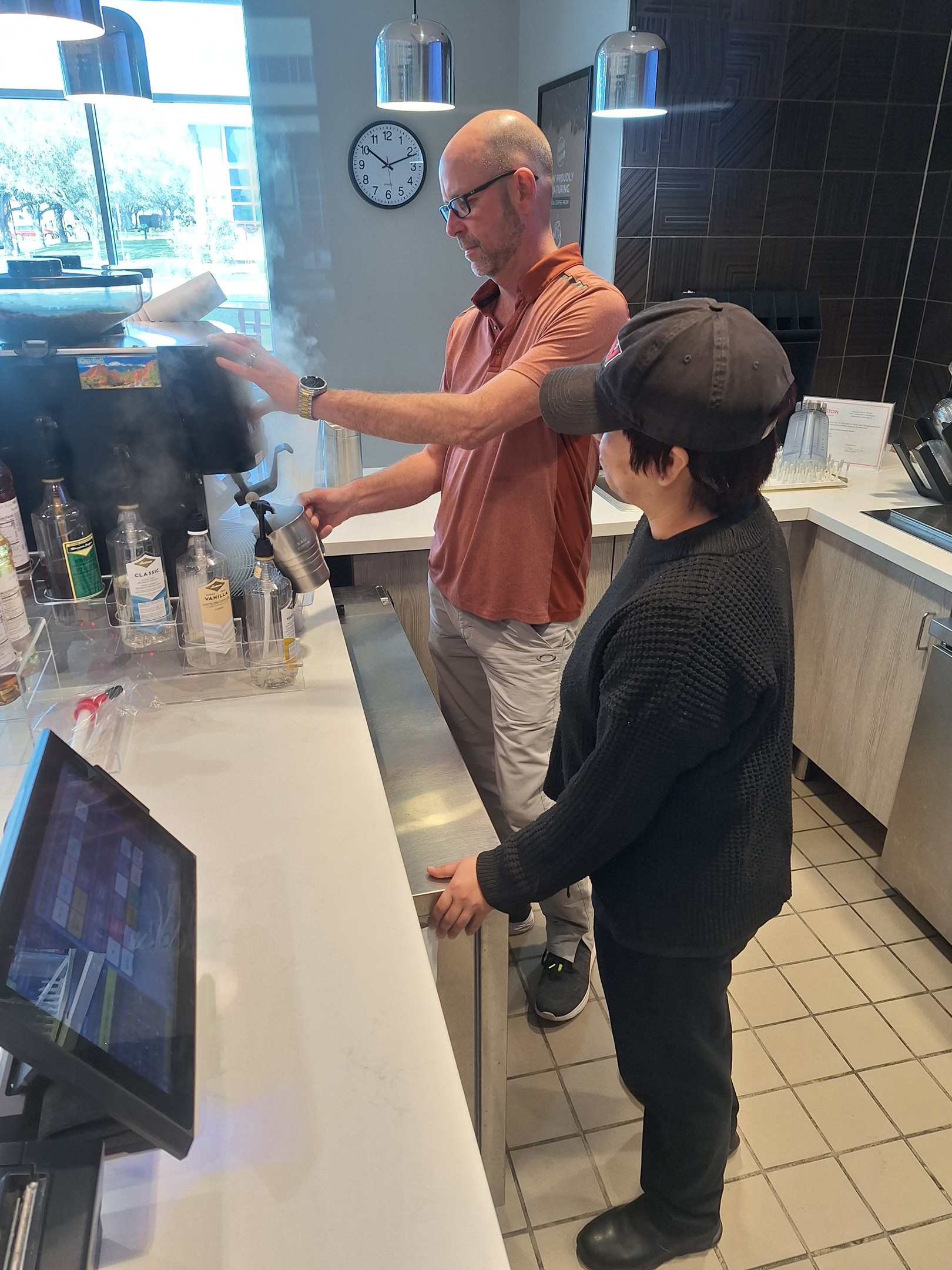 A man and a woman work a coffee machine.