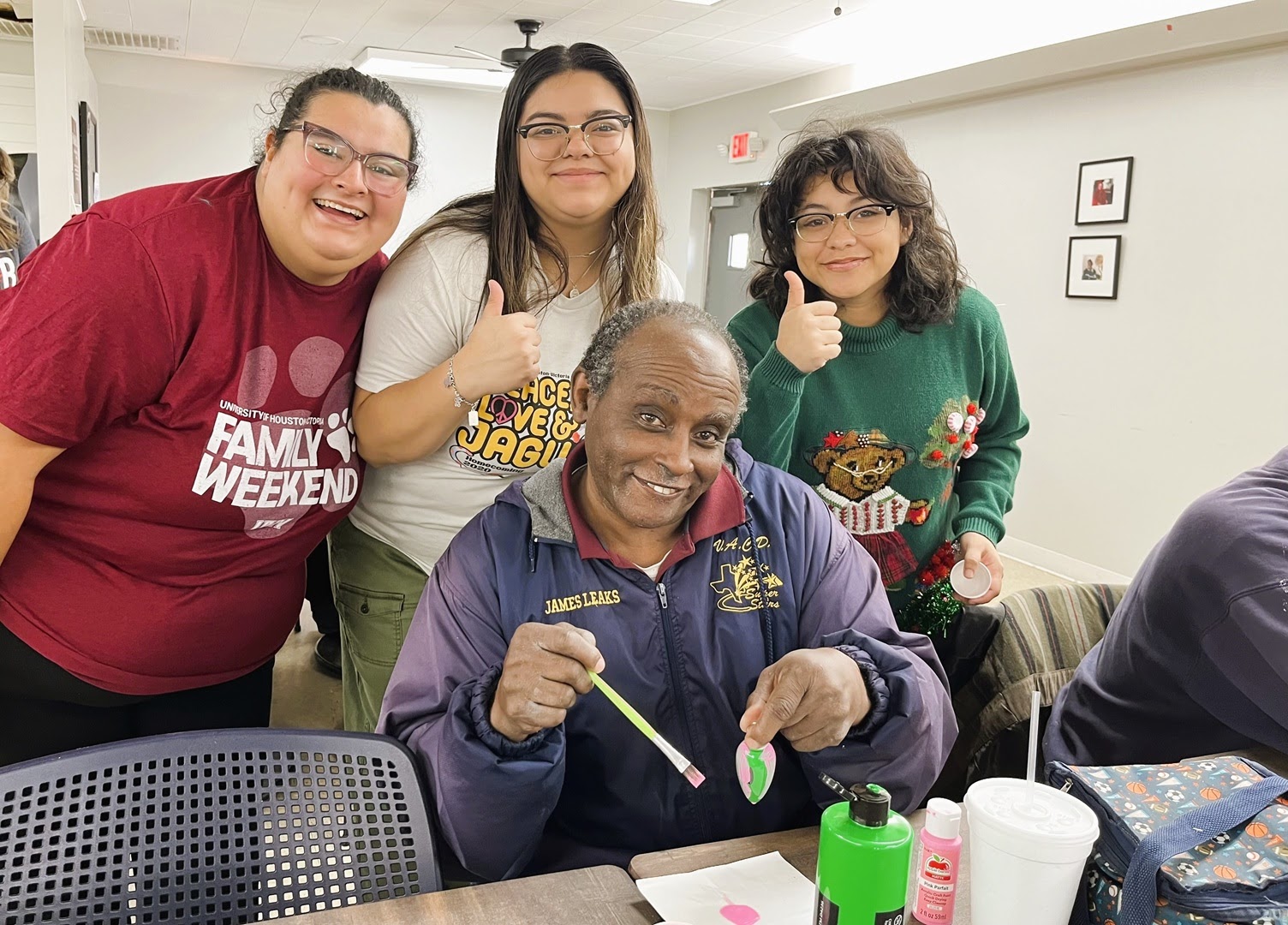 Three students pose with an elderly man at UHV Student Life’s 'Ornaments with the Elderly' event in December 2023.