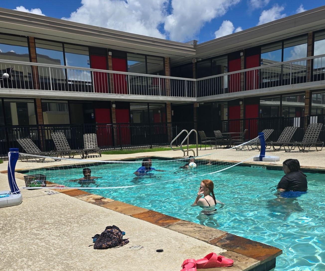 Five students play volleyball in a pool.