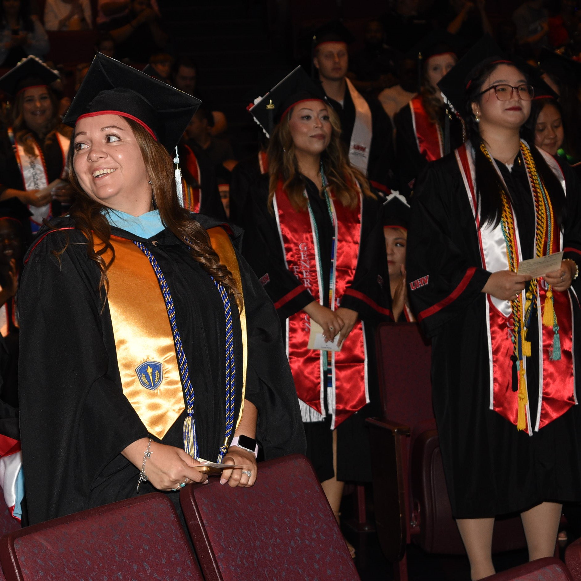 Graduates stand during the commencement ceremony.