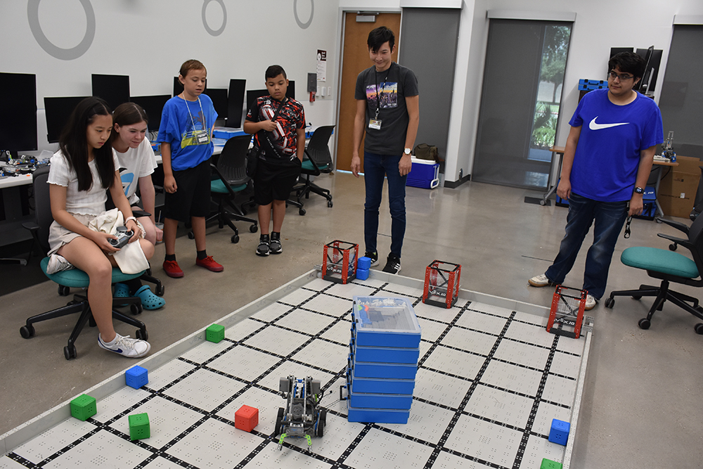 Students attending the UHV Texas Women in Computing summer camp for middle schoolers on Wednesday watch as Nadia Chu, far left, 13, drives a robot designed to pull a heavy stack of boxes.