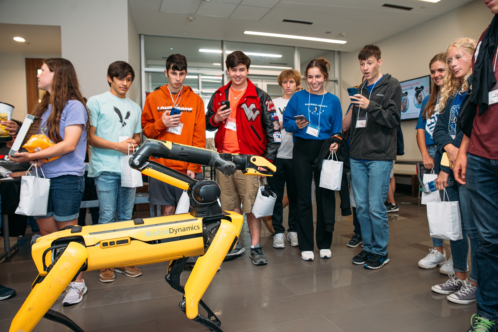 High school students watch a yellow robot