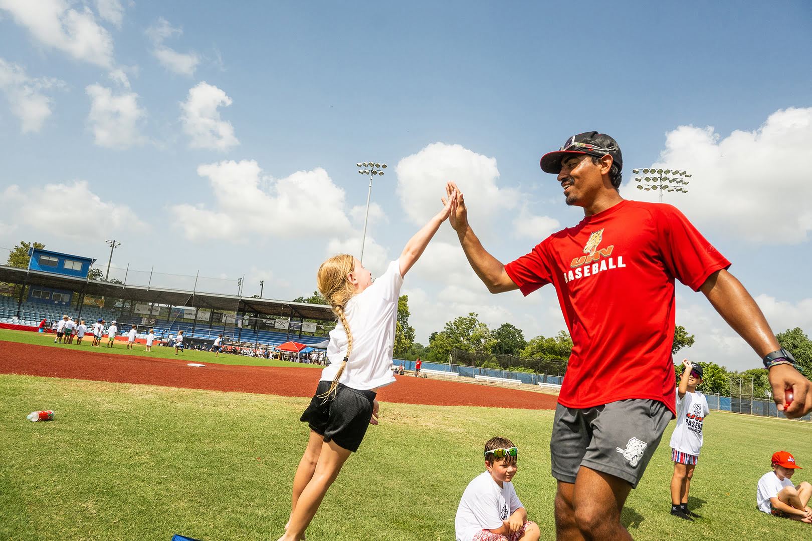 A girl high-fives her baseball camp coach.